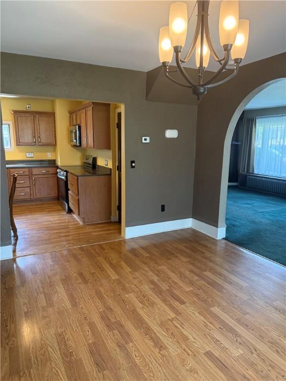 16 Cobbles E, Elmira, NY 14905 - kitchen with appliances with stainless steel finishes, arched walkways, dark countertops, open floor plan, and a chandelier