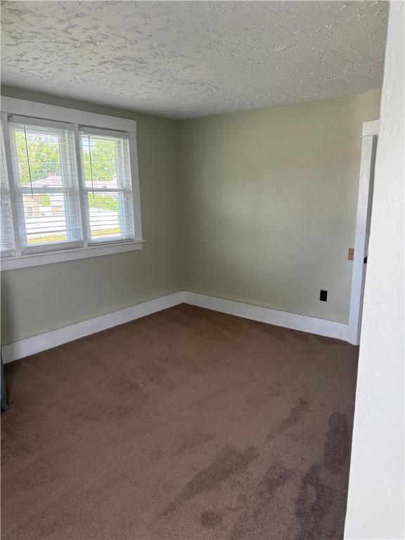16 Cobbles E, Elmira, NY 14905 - empty room featuring dark colored carpet, a textured ceiling, and baseboards