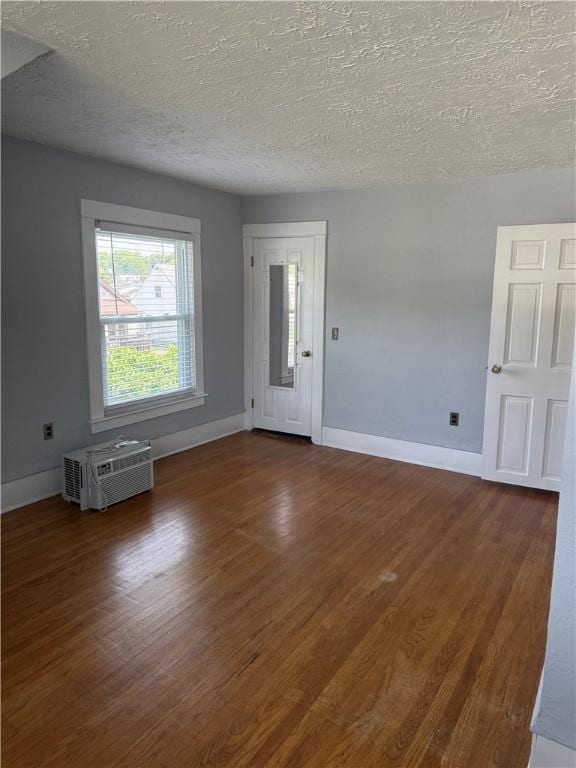 16 Cobbles E, Elmira, NY 14905 - unfurnished room with a wall mounted air conditioner, baseboards, dark wood-type flooring, and a textured ceiling