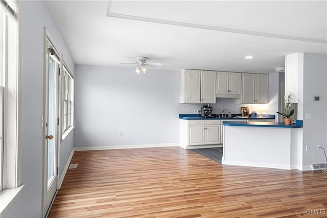 1 Wicklow Dr, Skaneateles, NY 13152 - kitchen featuring light wood finished floors, baseboards, ceiling fan, a sink, and dark countertops
