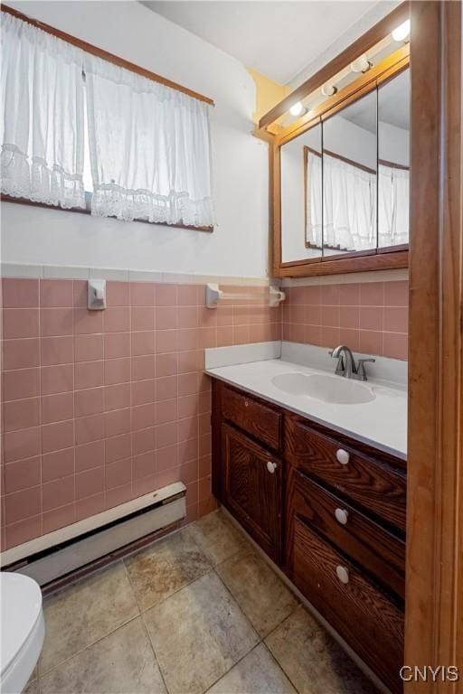 172 Nichols Ave, Syracuse, NY 13206 - bathroom featuring toilet, tile walls, vanity, baseboard heating, and a wainscoted wall