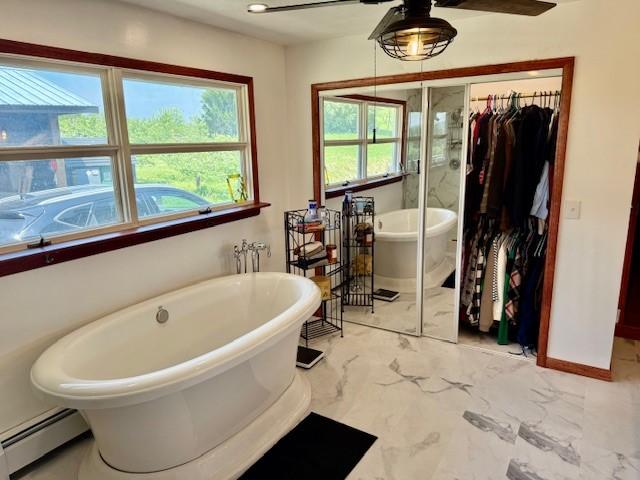 251 Pearsall Rd, Westford, NY 12155 - bathroom featuring a baseboard radiator, a spacious closet, a ceiling fan, and healthy amount of natural light