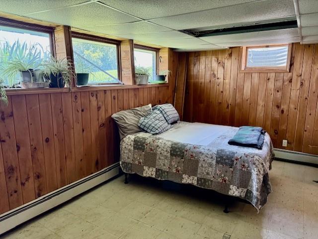 251 Pearsall Rd, Westford, NY 12155 - bedroom featuring baseboard heating, tile patterned floors, and wooden walls