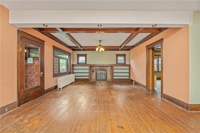 1579 Culver Rd, Rochester, NY 14609 - unfurnished living room featuring radiator, light wood-type flooring, a brick fireplace, baseboards, and coffered ceiling