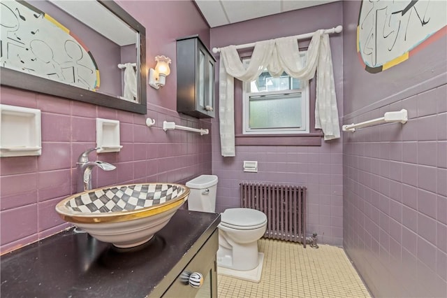 1579 Culver Rd, Rochester, NY 14609 - bathroom featuring radiator heating unit, tile walls, toilet, tile patterned floors, and a wainscoted wall