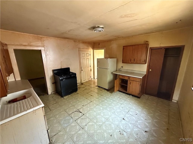 131 Lakeview Ave, Syracuse, NY 13204 - kitchen with freestanding refrigerator, black gas range, light flooring, light countertops, and brown cabinetry