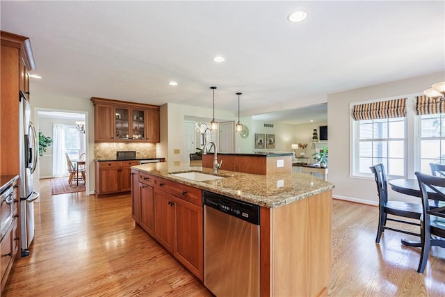 2 Princeton Ln, Perinton, NY 14450 - kitchen with stainless steel appliances, a sink, brown cabinetry, light wood-style flooring, and an island with sink