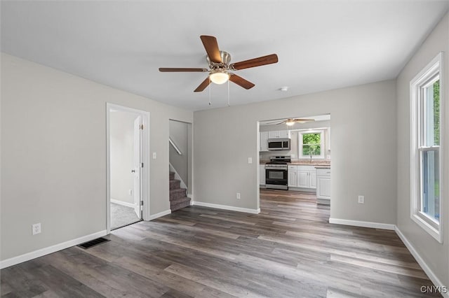 308 Lewis St, Syracuse, NY 13204 - unfurnished living room with plenty of natural light, stairway, dark wood-style floors, and a ceiling fan