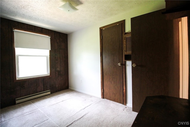 465 Blanding Rd, Sherburne, NY 13460 - unfurnished bedroom featuring baseboard heating, light colored carpet, a textured ceiling, and wooden walls