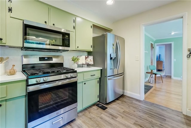 12 Edgewood Dr, Penfield, NY 14526 - kitchen with stainless steel appliances, green cabinets, light countertops, ornamental molding, and light wood-style flooring