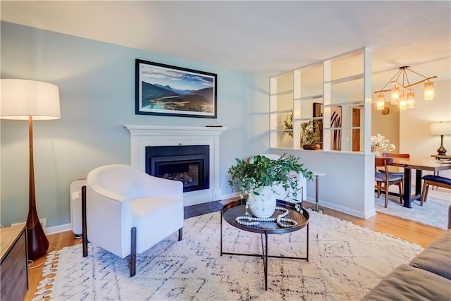 12 Edgewood Dr, Penfield, NY 14526 - living room with wood finished floors, a chandelier, a glass covered fireplace, and baseboards