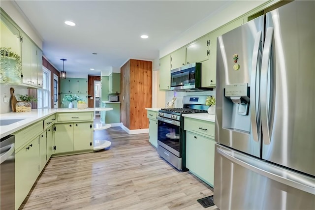 12 Edgewood Dr, Penfield, NY 14526 - kitchen featuring stainless steel appliances, a peninsula, light countertops, light wood-type flooring, and green cabinetry