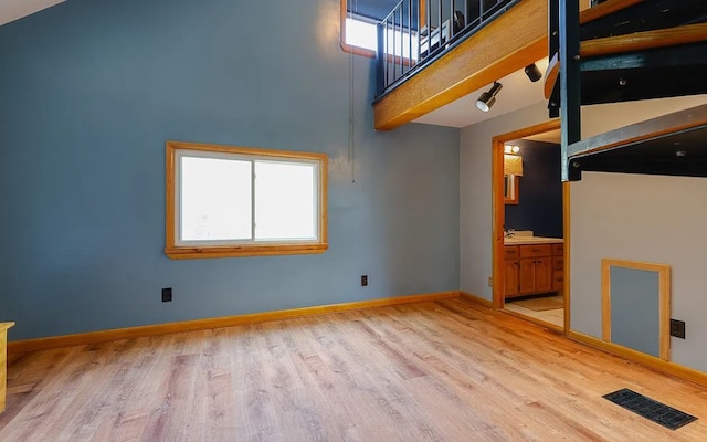 58 Mayflower St, Rochester, NY 14615 - unfurnished living room featuring light wood-type flooring, baseboards, and a towering ceiling