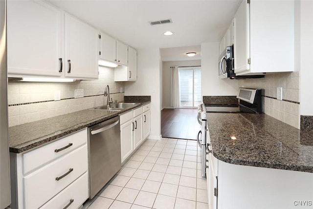 442 Summerhaven Dr N, Manlius, NY 13057 - kitchen with appliances with stainless steel finishes, a sink, light tile patterned flooring, white cabinets, and decorative backsplash