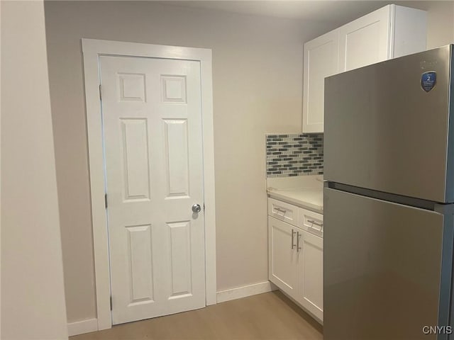530 Lenox Ave, Oneida, NY 13421 - kitchen with freestanding refrigerator, white cabinets, light countertops, light wood-style flooring, and decorative backsplash