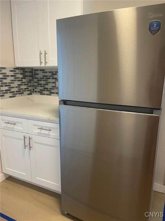 530 Lenox Ave, Oneida, NY 13421 - kitchen view of freestanding refrigerator, white cabinets, light wood-style floors, decorative backsplash, and light stone counters