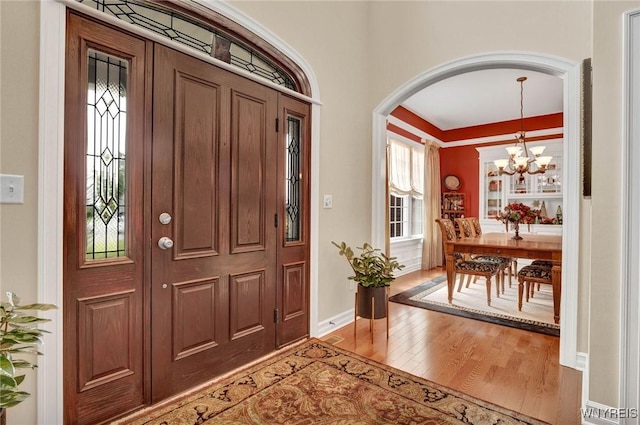 81 Hidden Oaks Ct, Grand Island, NY 14072 - entryway featuring wood finished floors, a chandelier, arched walkways, baseboards, and ornamental molding
