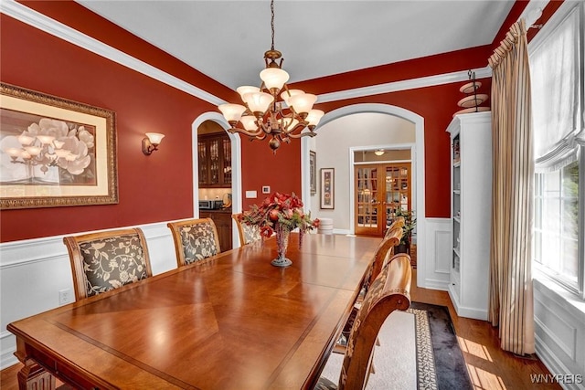81 Hidden Oaks Ct, Grand Island, NY 14072 - dining space with arched walkways, a chandelier, a wainscoted wall, and wood finished floors