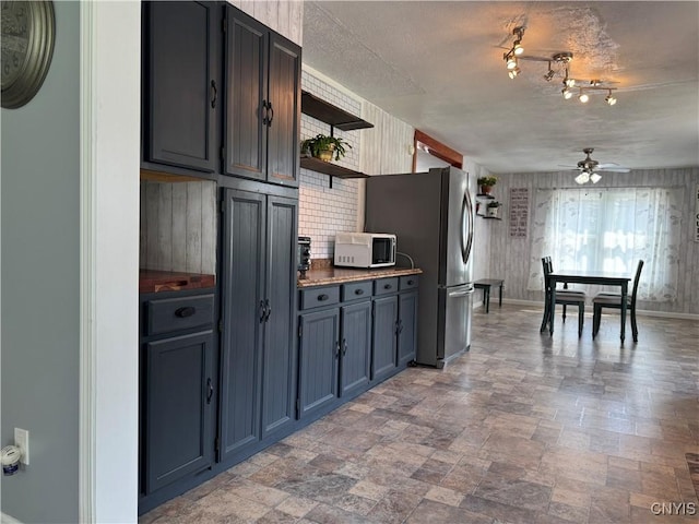 236 Harry Bryant Rd, Amboy, NY 13493 - kitchen with ceiling fan, freestanding refrigerator, white microwave, open shelves, and stone finish floors