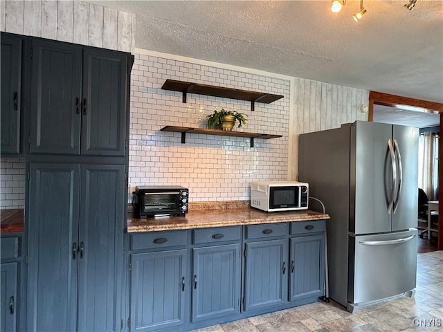236 Harry Bryant Rd, Amboy, NY 13493 - kitchen with white microwave, freestanding refrigerator, a textured ceiling, blue cabinets, and dark countertops