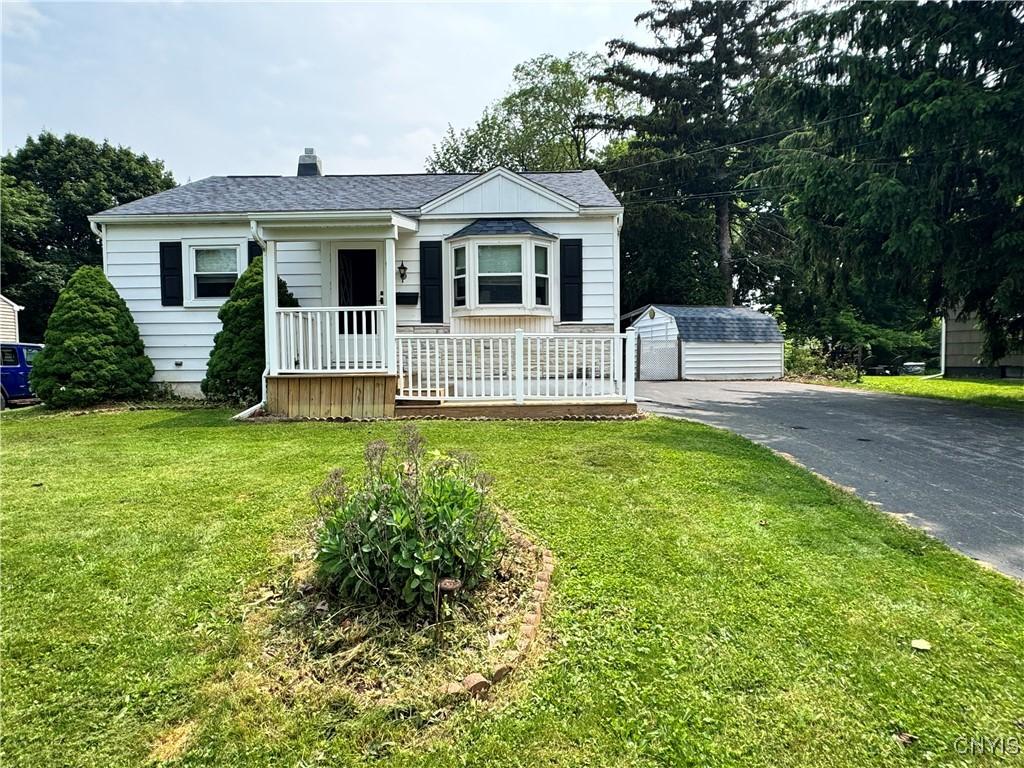 104 Lansdale Rd, Dewitt, NY 13057 - bungalow with an outbuilding, a front yard, a chimney, covered porch, and a shingled roof