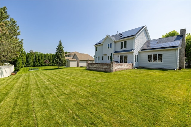 204 Red Hickory Dr, Greece, NY 14626 - back of property with roof mounted solar panels, a lawn, and a chimney