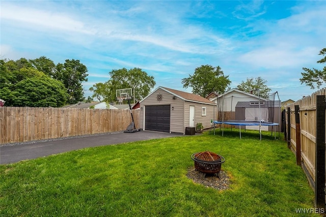 157 73rd St, Niagara Falls, NY 14304 - view of yard featuring an outbuilding, a garage, a fire pit, a trampoline, and asphalt driveway