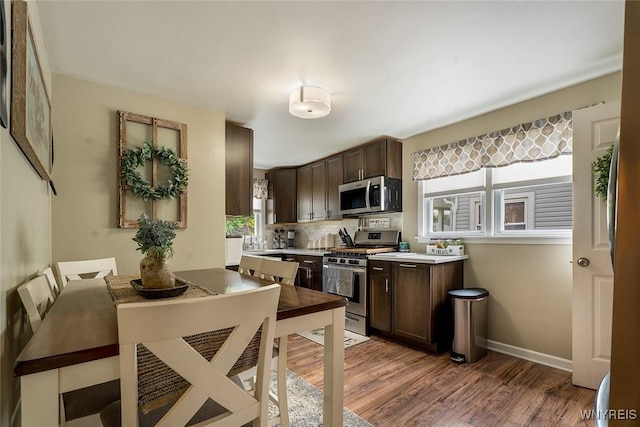157 73rd St, Niagara Falls, NY 14304 - kitchen featuring stainless steel appliances, dark brown cabinets, light wood-type flooring, light countertops, and tasteful backsplash
