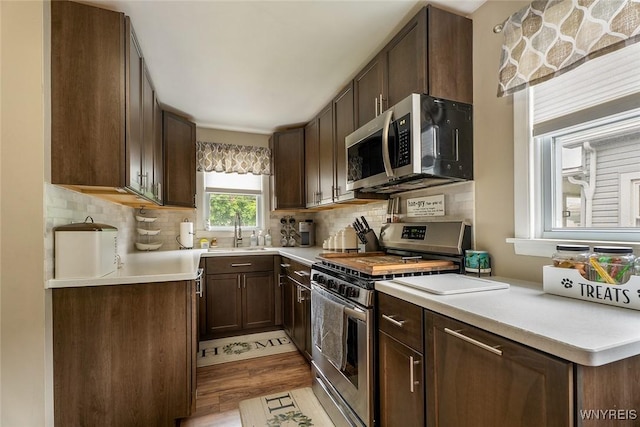 157 73rd St, Niagara Falls, NY 14304 - kitchen with appliances with stainless steel finishes, light countertops, decorative backsplash, light wood-type flooring, and dark brown cabinetry