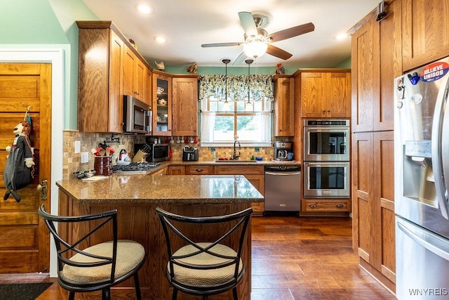 57 Savage Pl, Aurora, NY 14052 - kitchen featuring stainless steel appliances, a peninsula, brown cabinets, glass insert cabinets, and dark wood-style flooring