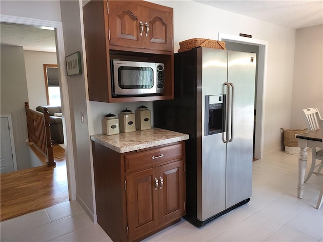 76 Belaire Dr, Big Flats, NY 14845 - kitchen with appliances with stainless steel finishes, light countertops, light tile patterned floors, baseboards, and brown cabinetry