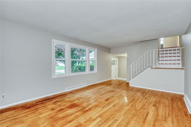 54 Hillary Dr, Chili, NY 14624 - unfurnished living room featuring wood finished floors, baseboard heating, stairs, and baseboards