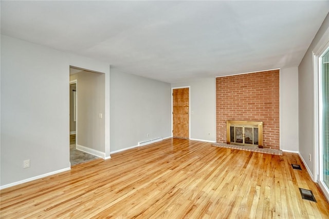 54 Hillary Dr, Chili, NY 14624 - unfurnished living room featuring wood-type flooring, baseboard heating, a brick fireplace, and baseboards