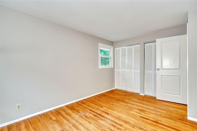 54 Hillary Dr, Chili, NY 14624 - unfurnished bedroom with light wood-style flooring, baseboards, and multiple closets