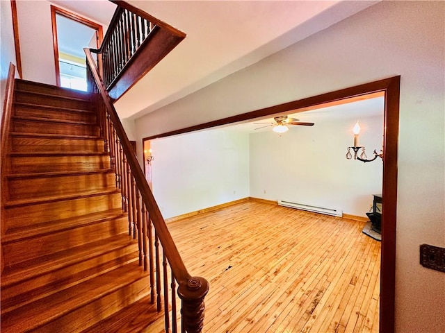 6956 E Washington St, Bath, NY 14810 - staircase with a baseboard heating unit, wood-type flooring, ceiling fan, and a wood stove