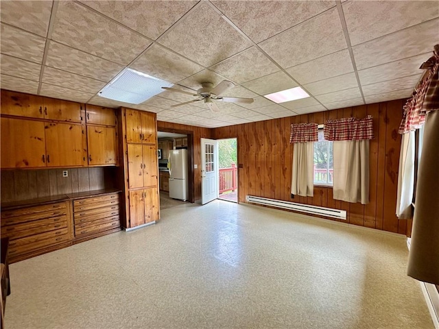 6956 E Washington St, Bath, NY 14810 - unfurnished living room with a baseboard heating unit, ceiling fan, wooden walls, light flooring, and a paneled ceiling