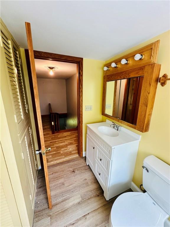 6956 E Washington St, Bath, NY 14810 - bathroom featuring toilet, wood finished floors, vanity, and baseboards