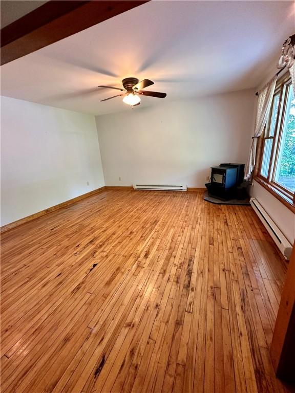 6956 E Washington St, Bath, NY 14810 - unfurnished room with a wood stove, baseboard heating, and light wood finished floors