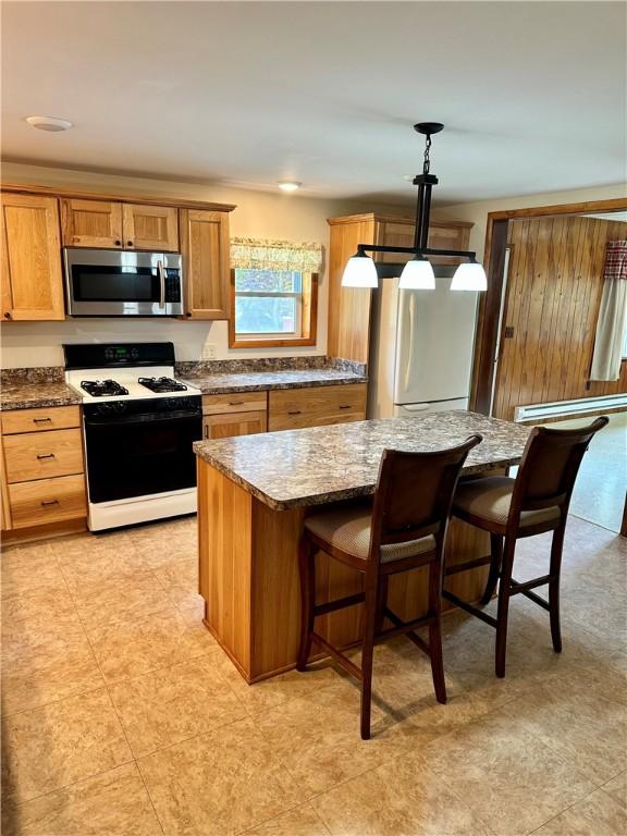 6956 E Washington St, Bath, NY 14810 - kitchen with stainless steel microwave, range with gas cooktop, fridge, a center island, and a breakfast bar area