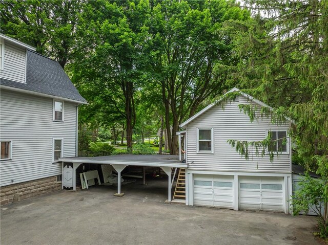 40 Washington Rd, Pittsford, NY 14534 - view of home's exterior featuring a shingled roof, a garage, driveway, and view of wooded area