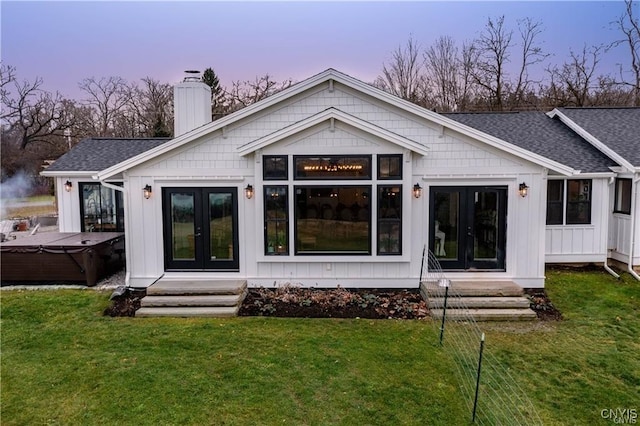 4500 W Lake Rd, Niles, NY 13152 - back of house at dusk with a hot tub, french doors, a chimney, and roof with shingles
