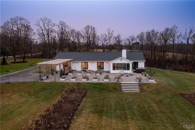 4500 W Lake Rd, Niles, NY 13152 - back of house at dusk featuring a patio, a chimney, and a lawn