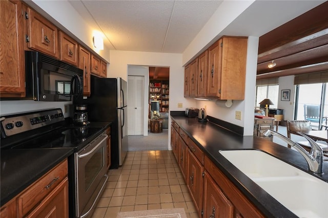 135 Cliffside Dr, South Bristol, NY 14424 - kitchen with stainless steel appliances, a sink, dark countertops, brown cabinetry, and a textured ceiling