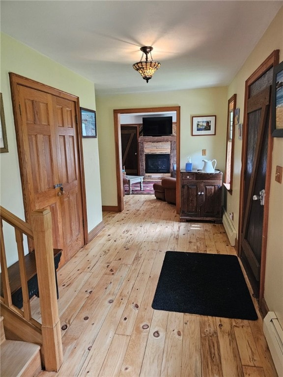 139 Pheasant Run Rd, Middlefield, NY 13326 - entryway with a baseboard heating unit, light wood-style floors, a glass covered fireplace, and stairway