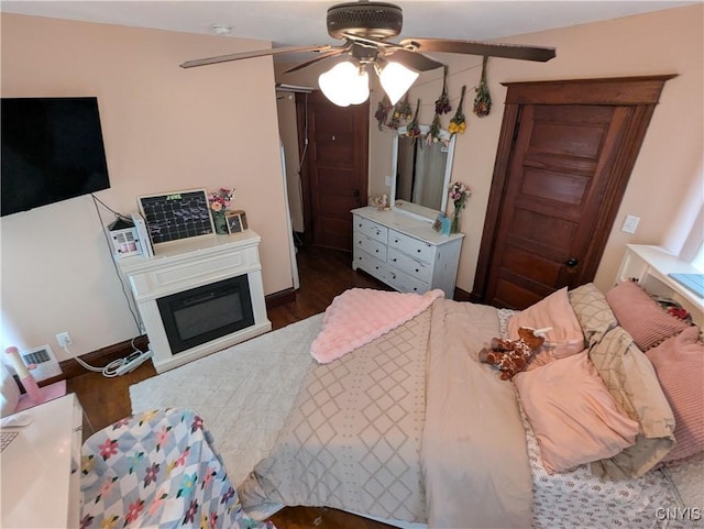 2976 Cataract St, Denmark, NY 13626 - bedroom featuring dark wood-style floors, a glass covered fireplace, and a ceiling fan
