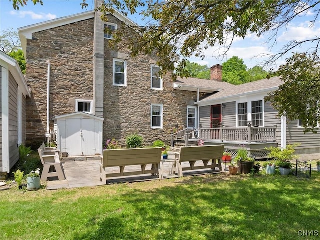 8796 State Highway 12, Sherburne, NY 13460 - rear view of house featuring stone siding, a wooden deck, a lawn, and a chimney