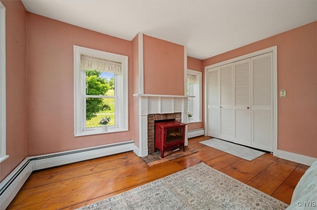 8796 State Highway 12, Sherburne, NY 13460 - unfurnished living room featuring a baseboard heating unit, hardwood / wood-style flooring, baseboards, and a wood stove