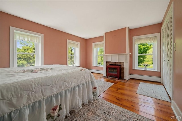 8796 State Highway 12, Sherburne, NY 13460 - bedroom featuring a baseboard radiator, wood-type flooring, a fireplace, and baseboards