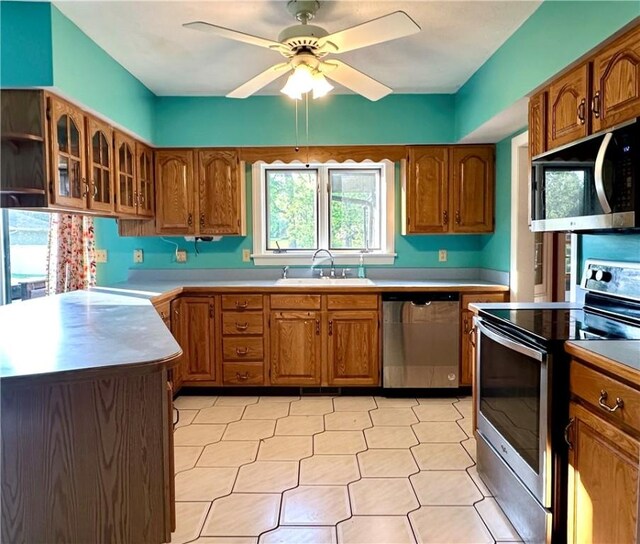 966 W Church St, Elmira, NY 14905 - kitchen featuring stainless steel appliances, a sink, brown cabinetry, and glass insert cabinets