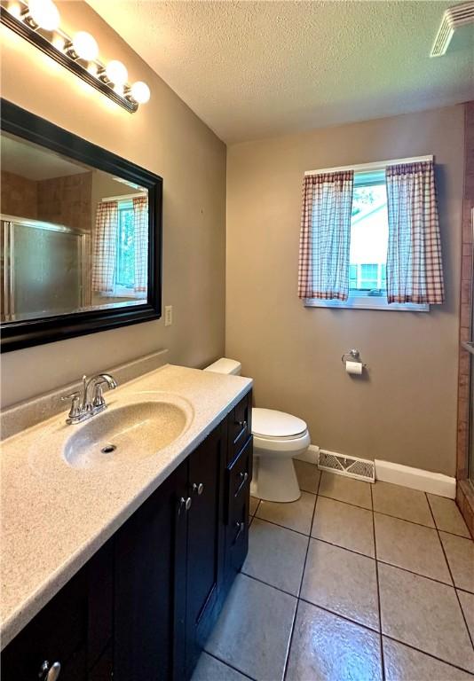 966 W Church St, Elmira, NY 14905 - full bathroom featuring vanity, a stall shower, a textured ceiling, toilet, and tile patterned floors